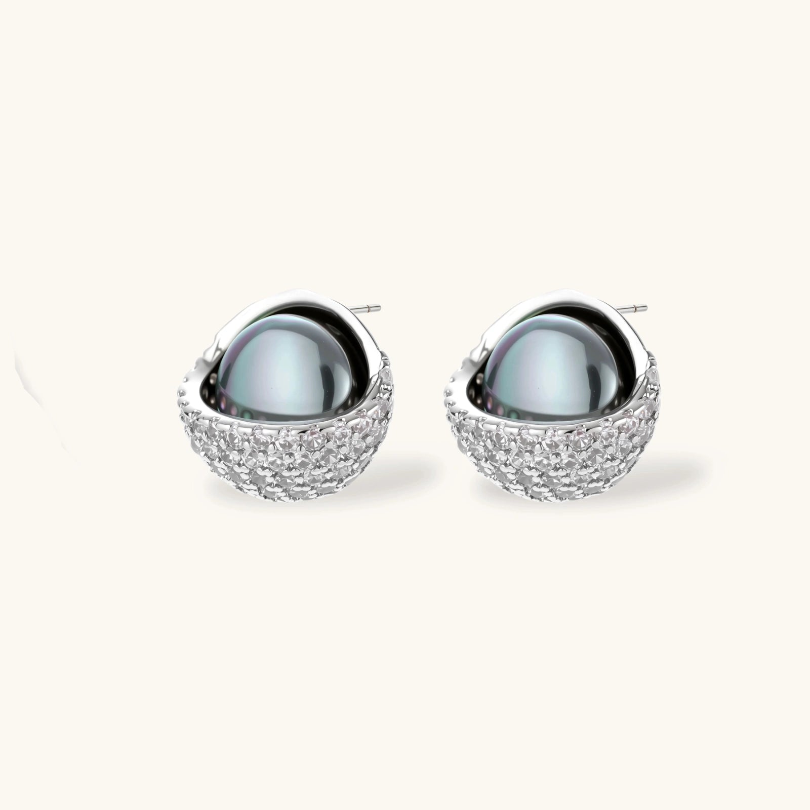 White gold plated spherical jewelry set with zirconia crystal pavé and dark lustrous centers on neutral background.